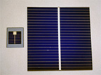 Two deep blue solar cell samples.  Small square cell to left, and larger square cell to right. Each sample is covered by very narrow horizontal lines and one wider vertical line.