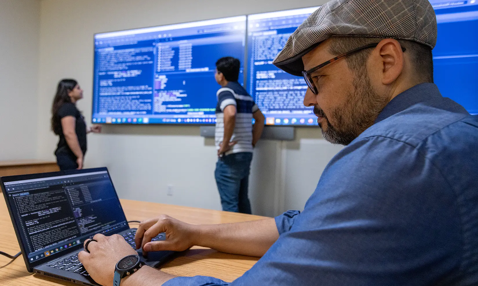 economic-life-cycle-market-analysis-94326 Two researchers examine data on large wall monitors while another researcher views data on a laptop.