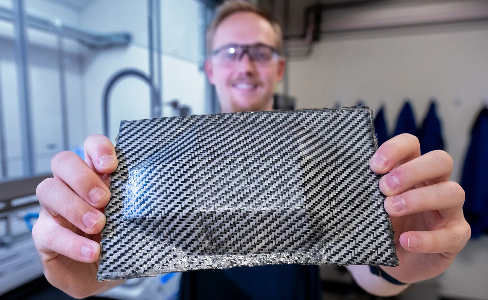 recovery-reuse-redesign-of-waste-plastics-85485 A researcher holds up a hybrid carbon fiber composite with enhanced ductility, utilizing PolyEster Covalently Adaptable Network resin.