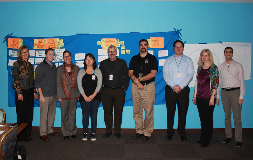 A group of people stand in front of a wall. 
