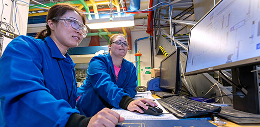 licensing-73179 Two people look at a computer monitor while wearing safety glasses.